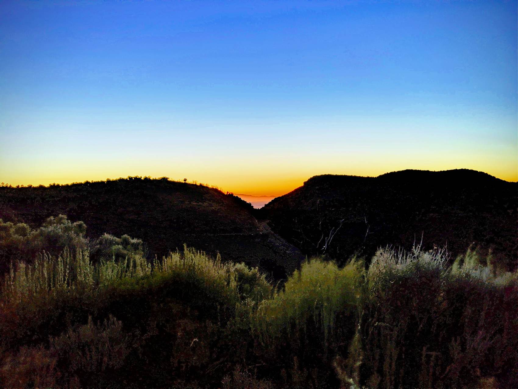 Twilight gradient from deep blue to orange over dark ridgelines